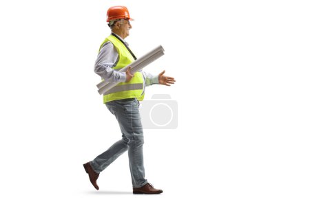 Téléchargez les photos : Plan de profil complet d'un ingénieur mâle mature portant des plans et marchant isolé sur fond blanc - en image libre de droit