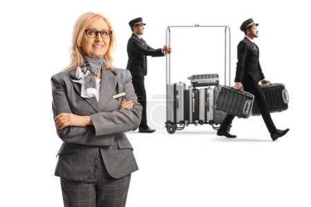 Photo for Bellboys carrying suitcases with a luggage cart and female hotel manager posing isolated on white background - Royalty Free Image