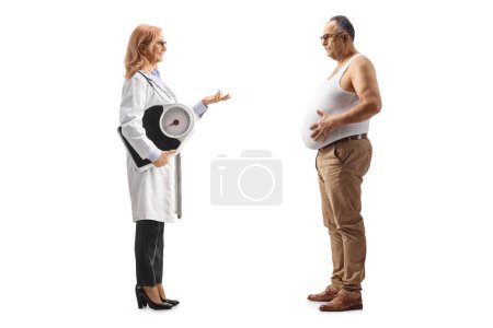 Foto de Foto de perfil completo de una doctora sosteniendo una báscula de peso y hablando con un hombre maduro con sobrepeso aislado sobre fondo blanco - Imagen libre de derechos