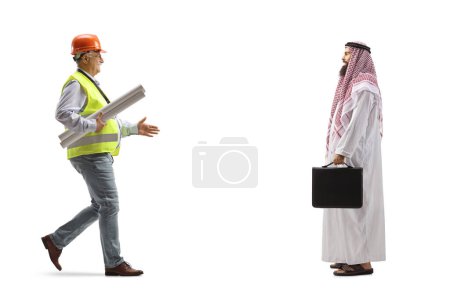 Photo for Full length profile shot of a mature male engineer carrying blueprints and meeting an arab man isolated on white background - Royalty Free Image