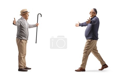 Téléchargez les photos : Vue de profil pleine longueur d'un homme mûr marchant vers un homme âgé avec les bras grands ouverts isolés sur fond blanc - en image libre de droit