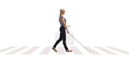 Foto de Foto de perfil completo de una joven ciega caminando con un bastón blanco en un cruce peatonal aislado sobre fondo blanco - Imagen libre de derechos