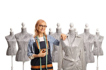 Téléchargez les photos : Couturière tenant des ciseaux à côté d'une robe sur un mannequin poupée isolé sur fond blanc - en image libre de droit