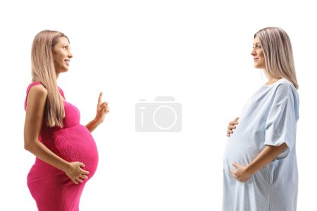 Foto de Dos mujeres embarazadas jóvenes teniendo una conversación aislada sobre fondo blanco - Imagen libre de derechos