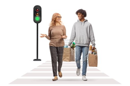 Photo for African american guy carrying grocery bags and having a conversation with a caucasian mature woman at a pedestrian crossing isolated on white background - Royalty Free Image