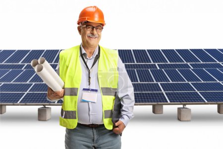 Foto de Ingeniero masculino maduro sosteniendo planos de impresión frente a paneles fotovoltaicos aislados sobre fondo blanco - Imagen libre de derechos