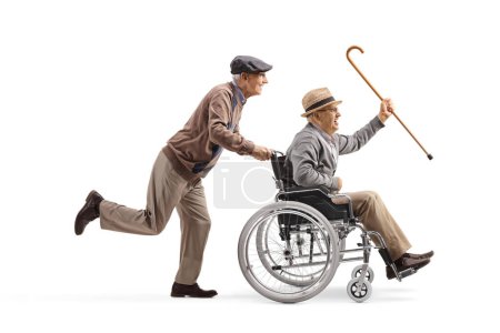 Téléchargez les photos : Homme âgé poussant un aîné dans un fauteuil roulant et tenant une canne isolée sur fond blanc - en image libre de droit