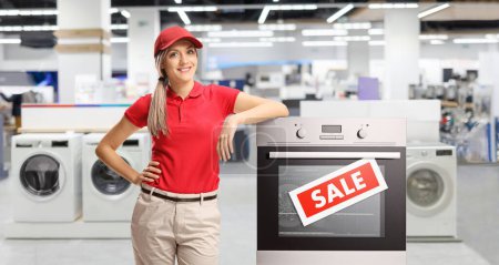 Photo for Female sale asisstant standing next to an electrcal oven inside a shopping mall - Royalty Free Image