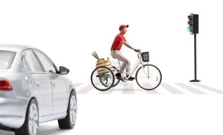 Foto de Tipo montando un triciclo con una caja de frutas y verduras en un cruce peatonal aislado sobre fondo blanco - Imagen libre de derechos