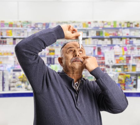 Foto de Hombre maduro aplicando gotas para los ojos en la farmacia - Imagen libre de derechos