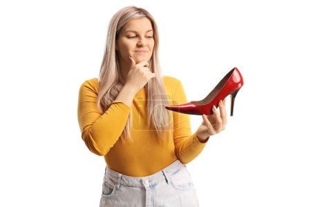 Photo for Young woman holding a red high heel shoe and thinking isolated on white background - Royalty Free Image