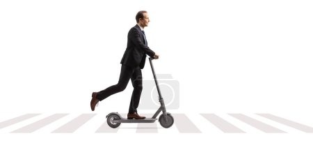 Foto de Foto de perfil completo de un hombre de negocios montando un scooter eléctrico en un cruce de cebra peatonal aislado sobre fondo blanco - Imagen libre de derechos