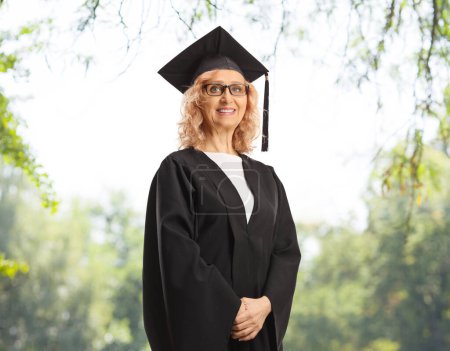Téléchargez les photos : Marture femme portant une robe de diplômé et posant à l'extérieur - en image libre de droit