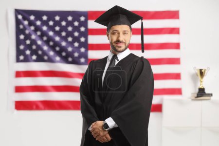 Photo for Man wearing a graduate gown and posing in front of a USA flag - Royalty Free Image