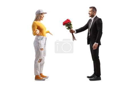 Téléchargez les photos : Profil complet d'un homme d'affaires donnant un bouquet de roses à une jeune femme occasionnelle isolée sur fond blanc - en image libre de droit