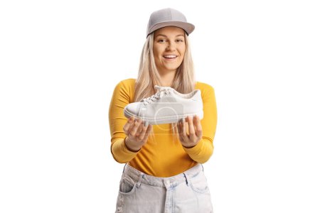 Téléchargez les photos : Jeune femelle excitée tenant une sneaker blanche isolée sur fond blanc - en image libre de droit