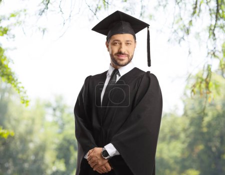 Photo for Man wearing a graduate gown and posing outdoors in a park - Royalty Free Image