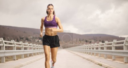 Foto de Atleta corriendo por un puente en un día nublado - Imagen libre de derechos