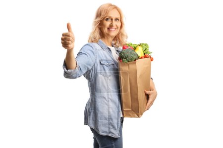 Foto de Mujer con una bolsa de comestibles sonriendo y mostrando los pulgares hacia arriba aislado sobre fondo blanco - Imagen libre de derechos