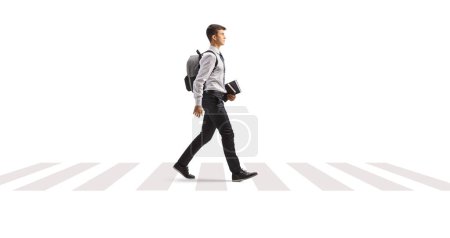 Téléchargez les photos : Étudiant avec un sac à dos en chemise et cravate tenant des livres et marchant à un passage à niveau piéton zèbre isolé sur fond blanc - en image libre de droit
