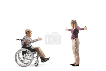 Foto de Mujer joven encontrándose con un anciano en silla de ruedas aislado sobre fondo blanco - Imagen libre de derechos