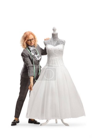 Photo for Woman measuring a bridal gown on a mannequin doll isolated on white background - Royalty Free Image