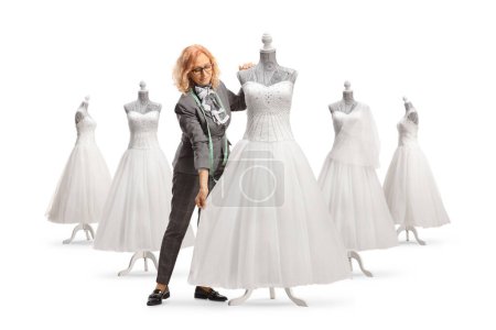 Photo for Seamstress measuring a bridal gown on a mannequin doll isolated on white background - Royalty Free Image