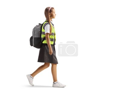 Photo for Full length profile shot of a schoolgirl wearing a reflective vest and walking isolated on white background - Royalty Free Image
