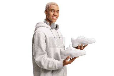 Photo for African american young man holding a pair of white sneakers isolated on white background - Royalty Free Image