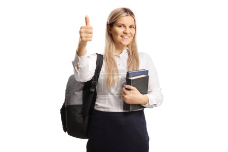 Photo for Cheeful female student holding books and showing a thumb up sign isolated on white background - Royalty Free Image