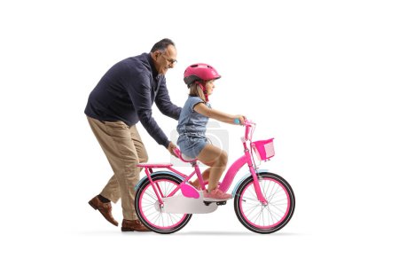 Téléchargez les photos : Photo de profil d'un grand-père aidant une fille à faire du vélo isolé sur fond blanc - en image libre de droit