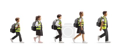 Photo for Full length profile shot of a group of schoolchildren with safety vests walking in a line isolated on white background - Royalty Free Image