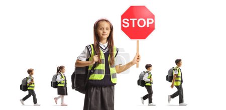 Téléchargez les photos : Écolière avec gilets de sécurité tenant un panneau stop et écoliers marchant derrière isolé sur fond blanc - en image libre de droit