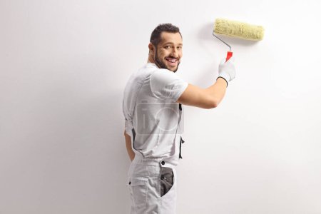 Foto de Pintor de casa alegre usando un rodillo de pintura y pintando una pared - Imagen libre de derechos