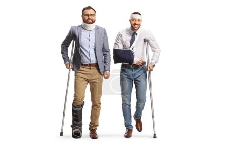 Foto de Dos jóvenes heridos de pie con muletas aisladas sobre fondo blanco - Imagen libre de derechos