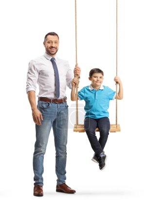 Téléchargez les photos : Portrait pleine longueur d'un père debout nexto à un garçon sur une balançoire isolé sur fond blanc - en image libre de droit