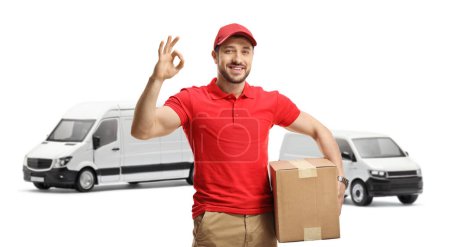Photo for Delivery man with a package gesturing a great sign in front of transport vans isolated on white background - Royalty Free Image