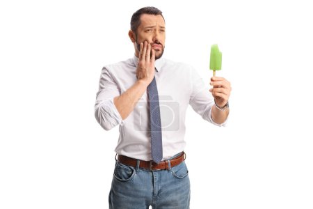 Téléchargez les photos : Homme tenant une crème glacée et ayant un mal de dents isolé sur fond blanc - en image libre de droit