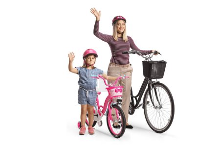 Téléchargez les photos : Petite fille avec sa mère agitant et debout avec un vélo isolé sur fond blanc - en image libre de droit