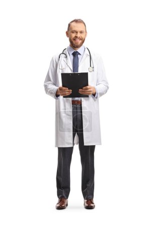 Photo for Full length portrait of a male physician smiling and holding a clipboard isolated on white background - Royalty Free Image