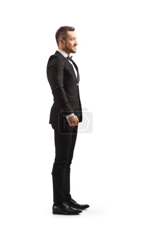 Photo for Full length profile shot of a bridegroom in a black suit isolated on white background - Royalty Free Image