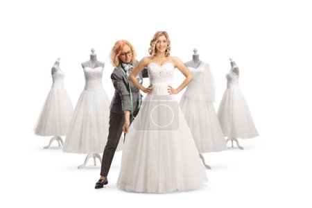 Téléchargez les photos : Créateur de mode prendre des mesures pour une robe de mariée isolé sur fond blanc isolé sur fond blanc - en image libre de droit