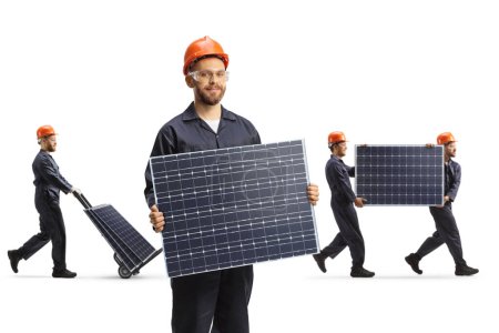 Foto de Trabajador de fábrica con un casco que sostiene un panel solar y otros trabajadores que llevan paneles en la parte posterior aislados sobre fondo blanco - Imagen libre de derechos