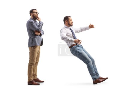 Téléchargez les photos : Photo de profil pleine longueur d'un homme pensif se tenant derrière un homme qui tombe isolé sur fond blanc - en image libre de droit