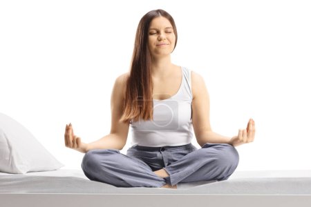 Foto de Mujer joven en pijama sentada en una pose de yoga aislada sobre fondo blanco - Imagen libre de derechos