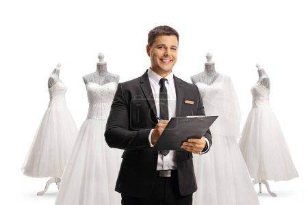 Téléchargez les photos : Jeune homme élégant dans un magasin de mariage tenant un presse-papiers et souriant isolé sur fond blanc - en image libre de droit