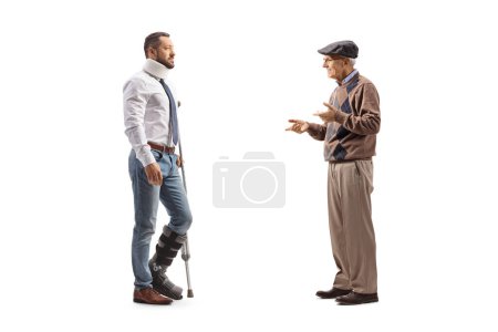 Foto de Foto de perfil completo de un hombre mayor hablando con un hombre herido con una muleta y cuello aislado sobre fondo blanco - Imagen libre de derechos