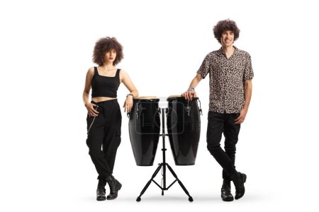 Photo for Full length portrait of a young male and female leaning on conga drums isolated on white background - Royalty Free Image
