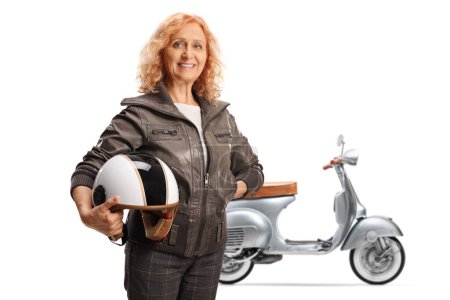 Téléchargez les photos : Femme mûre dans une veste en cuir devant un scooter tenant un casque isolé sur fond blanc - en image libre de droit