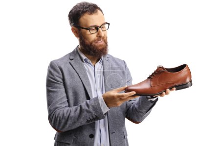 Téléchargez les photos : Homme barbu regardant une chaussure en cuir brun isolé sur fond blanc - en image libre de droit